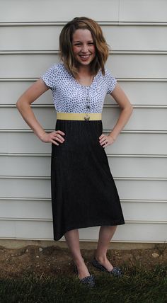 a woman standing in front of a white wall with her hands on her hips and smiling