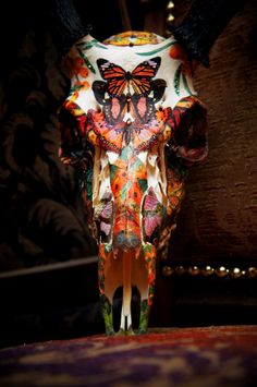 an animal skull is decorated with colorful butterflies