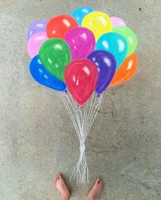 a person standing in front of a bunch of balloons with their feet on the ground