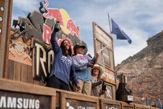 two men are standing in the back of a truck with their arms up and one man is throwing something into the air