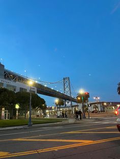 people crossing the street in front of a bridge