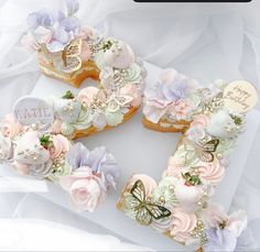 two heart shaped donuts decorated with flowers and butterflies on top of white tissue paper