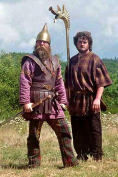 two men dressed in medieval clothing standing next to each other, one holding a staff