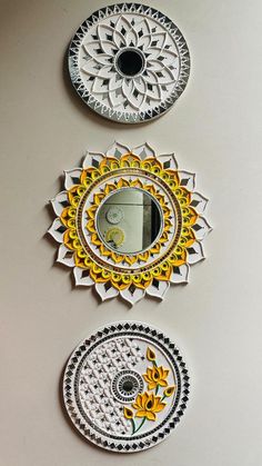 three circular mirrors hanging on the wall with designs painted on them in different colors and shapes