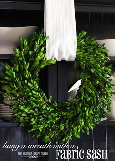 a wreath is hanging on the back of a hutch with dishes and utensils