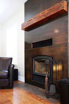 an empty living room with a fireplace and leather chair next to the fire place on the wall