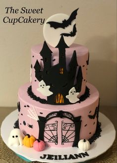 a pink cake decorated with black and white icing, spooky decorations and bats