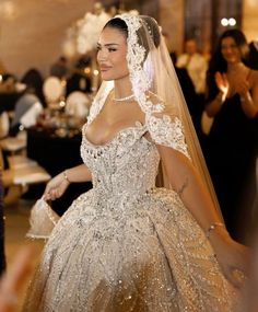 a woman in a wedding dress and veil walking down the aisle with her hand on her hip