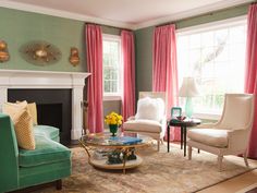 a living room filled with furniture and a fire place in front of a window covered in pink curtains