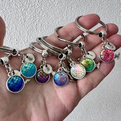 a person is holding six different key chains in their hand, one has a charm on it