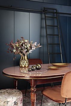 a vase with flowers sitting on top of a wooden table next to a chair and ladder