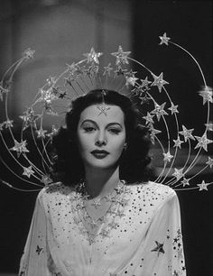 a black and white photo of a woman with stars in her hair, wearing a headpiece