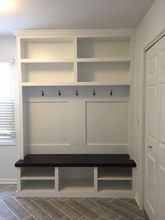 an empty room with white shelves and black bench