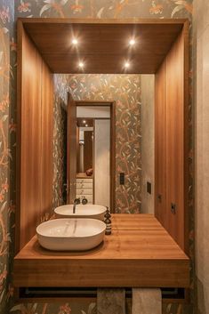 there is a sink in the middle of this bathroom with wood paneling and floral wallpaper