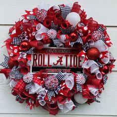 a red and white wreath on the side of a house with a roll & tide sign