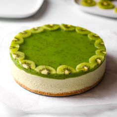 a green and white cheesecake with kiwi slices on it's crusts