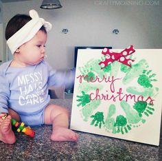 a baby sitting next to a christmas card