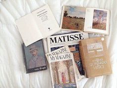 there are many books on the bed with white sheets and covers, including one for matissee