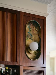 a wooden cabinet with a mirror on the wall above it and bottles in front of it