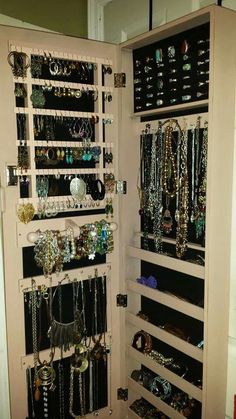 a closet filled with lots of jewelry and bracelets on shelves next to a door