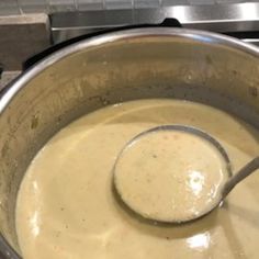 a ladle full of soup sitting on top of a stove