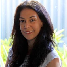 a woman with long dark hair smiling at the camera