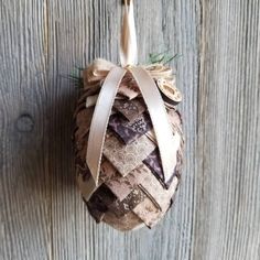 an ornament hanging on the side of a wooden wall with ribbon around it