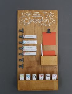 a wooden board with dice and notepads attached to the side, on top of a gray wall