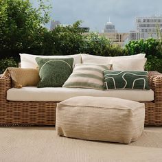 a wicker couch sitting on top of a wooden floor next to a green tree