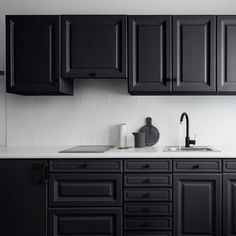 a kitchen with black cabinets and white counter tops