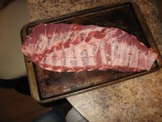 a piece of meat sitting on top of a metal pan next to a person's leg