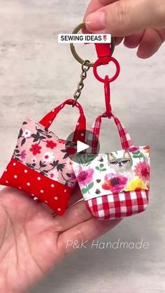 two small purses are being held up by someone's hand with a keychain