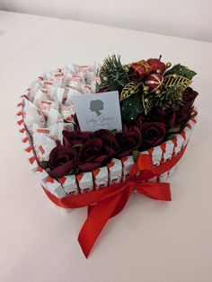 a heart shaped box filled with chocolates and flowers on top of a white table