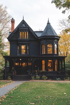 a large black house with lots of windows on it's front porch and stairs leading up to the second floor