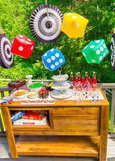 a wooden table topped with lots of food and drinks next to umbrellas hanging from the ceiling