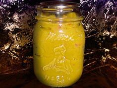 a glass jar filled with yellow liquid sitting on top of a table