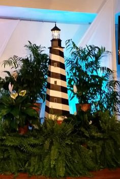 a black and white lighthouse surrounded by greenery