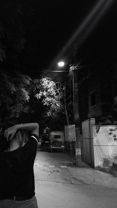 a man standing on the side of a road at night holding a baseball bat over his head