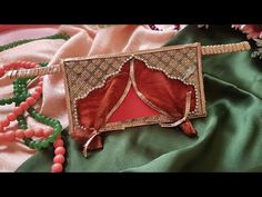 an elaborately decorated box sitting on top of a green satin covered table cloth next to beads