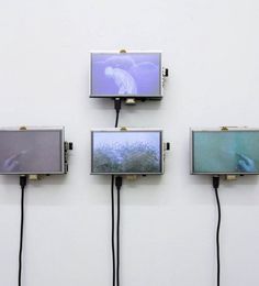 four televisions mounted to the side of a wall with wires running through them,