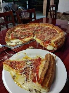 two pizzas sitting on top of a table with one slice missing from the pie