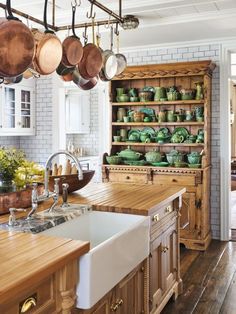 a kitchen filled with lots of pots and pans hanging from the ceiling next to a sink