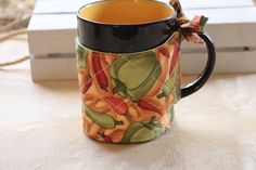 a coffee mug sitting on top of a wooden table next to a box with a bow