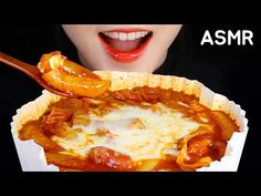 a woman holding a spoon over a bowl of food