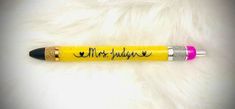 a yellow pen with writing on it sitting on top of a white fur covered surface