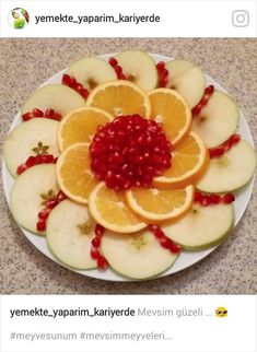 a plate with oranges, apples and pomegranates arranged on it