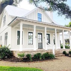 a white house with porches and columns on the front lawn, surrounded by trees