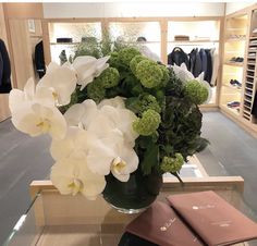 a vase filled with white flowers sitting on top of a table next to a book