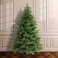 a small green christmas tree sitting on top of a wooden floor next to a wall