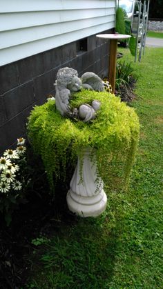 two stuffed animals sitting on top of a planter in the grass next to a house